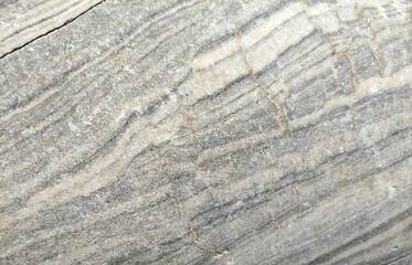 The texture of a gray marble stone with veins, cracks and inclusions