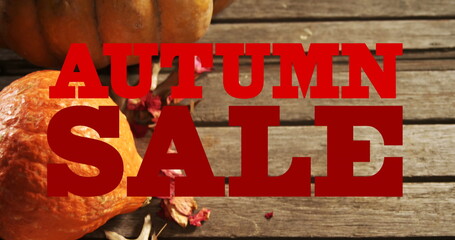 Image of autumn sale text in red letters over pumpkins and wooden boards