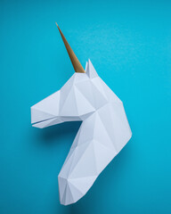 White 3d papercraft model of unicorn head on blue background. Minimal art concept. © Paopano