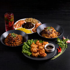 Korean food. Fried gyoza dumplings, Ramen, and assorted salads. on a black wooden background.