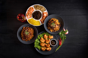 Korean food. Fried gyoza dumplings, Ramen, and assorted salads. on a black wooden background.