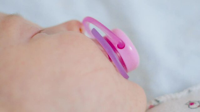 Newborn tranquility with a subtle pink pacifier resting alongside, highlighting moments of infancy peace.
