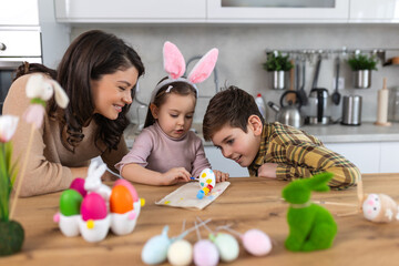 Happy easter. A mother, son and her daughter painting Easter eggs. Happy family preparing for...
