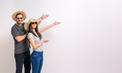 Cheerful boyfriend and girlfriend in hats and sunglasses showing copy space over white background