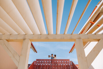 A young bride and groom tenderly embrace against the background of the blue sky. Wide format photo....