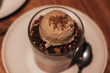 Delicious sweet chocolate ice cream in a transparent glass with chocolate chips and caramel cream. Top view