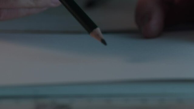 Hand drawing a straight lines with a pencil. Close-up, shallow dof.