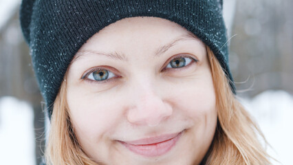 Portrait of beautiful smiling winter girl in black hat looking at camera.