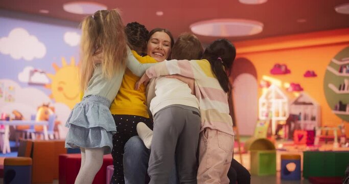 Young Kindergarten Teacher and Cute Multiethnic Children Having Fun. Joyful Kids are Happy to See Their Daycare Pedagogue, Boys and Girls Hugging Their Young Female Educator