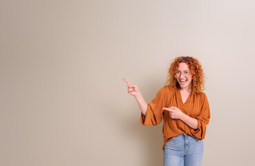 Cheerful young businesswoman with redhead aiming at copy space for advertisement on white background