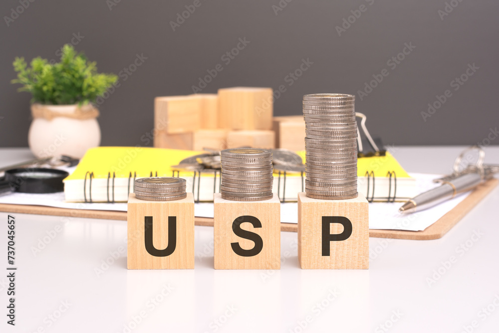 Aufkleber usp text in wooden blocks with coins stacked in increasing stacks. unique selling proposition concep
