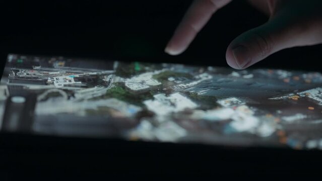 Person exploring satellite 3D view of a city map on a tablet touchscreen. Close up, slow motion. 