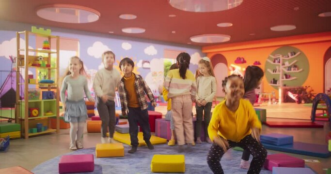 Cheerful Preschool Educator Dancing and Playing with Creative Multiethnic Kids in Kindergarten. Group of Small Adorable Children Playing Fun Active Workout Games Together