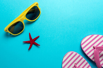 Creative composition with seashells, sunglasses and beach slippers on blue background. Summer...