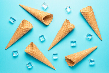 Various ice cream cones with ice cubes on blue background. Minimal summer concept.