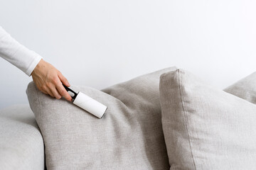Cropped view on woman hand cleaning sofa and pillow using lint roller