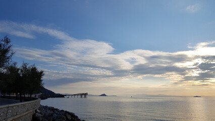 A serene body of water stretches out before you, with a white clouds and blue sky above