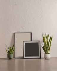 Grey stone wall background and floor, vase of green plant, desk, laptop and frame.