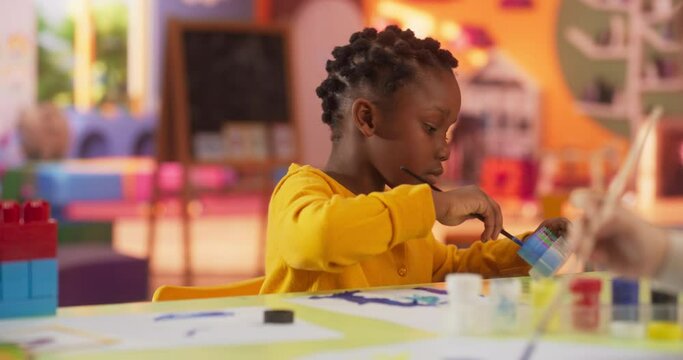 Portrait of an Adorable Stylish Black Girl Using Watercolor to Create a Colorful Painting. Cheerful African Child Spending Productive Time in Preschool, Learning to Paint in Art Class