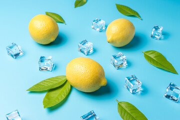 Creative summer composition with lemon and ice cubes on blue background. Minimal drink concept.