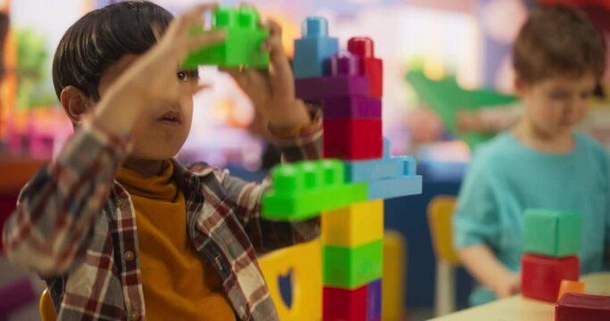 Cute Indian Boy Constructing a Toy Tower Out of Building Blocks. Caucasian Boy and African Girl Playing Together with Colorful Plastic Bricks. Smart Adorable Children Spend Time in Kindergarten