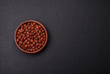 Delicious hazelnut whole, raw, without shell, on a dark concrete background
