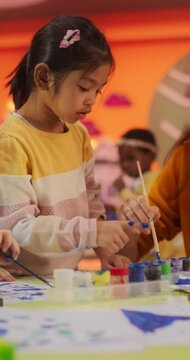 Vertical Screen: Adorable Multiethnic Girls Using Watercolor to Create Colorful Paintings on Paper. Cheerful Female Teacher Spending Productive Time in Preschool, Teaching Kids to Paint in Art Class