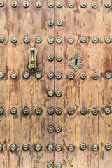 Forged metal vintage door knocker on brown wooden door