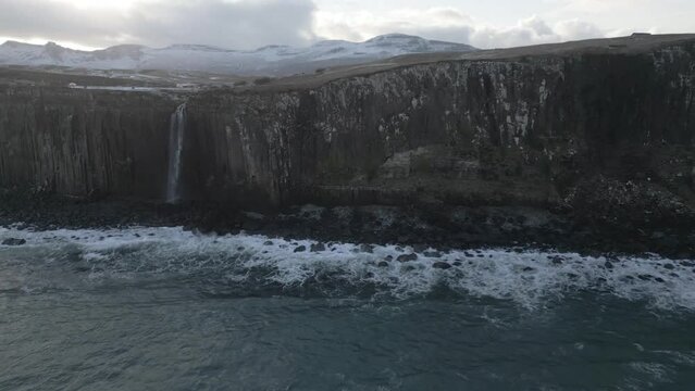 Kilt rock and mealt falls in scotland with snow-covered hills in the background, overcast weather, aerial view