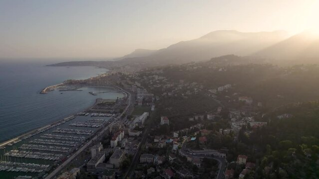Seaside town of Menton France in the Blue southern Mediterranean coast during sunset with Marina, Aerial dolly out shot