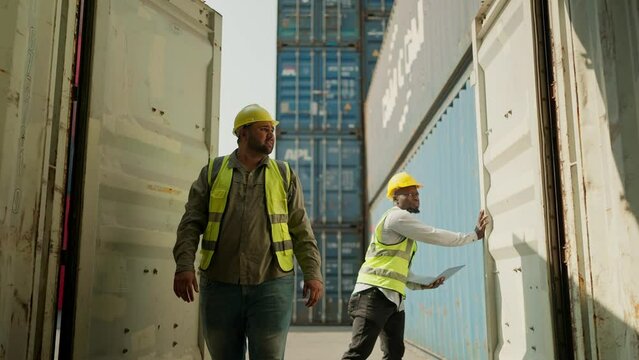 Two cargo workers in safety uniform open container box checking goods in shipping import export logistic port. Workers opening shipping cargo container in logistics terminal. Cargo and shipping