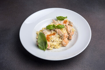 Fototapeta na wymiar Pasta with salmon, cream sauce and basil on a white plate