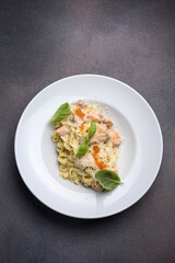 Pasta with salmon, cream sauce and basil on a white plate