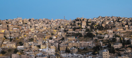 Captivating panoramic view of skyline of Amman, Jordan traditional houses atop a picturesque hill during blue hour - 737103409