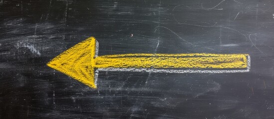 Bright yellow arrow pointing on blackboard displaying direction concept