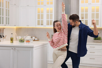 Happy lovely couple dancing together in kitchen