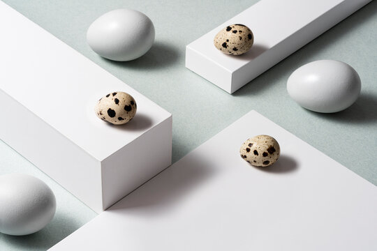White eggs and quaill eggs on layered background, still life, high angle shot