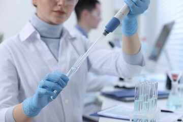 Scientist dripping sample into test tube in laboratory, closeup