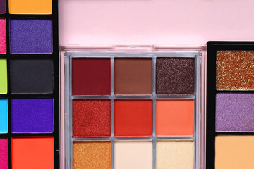 Various colorful eyeshadow palettes on bright pink background. Flat lay.