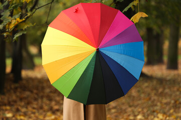 Woman with rainbow umbrella in autumn park