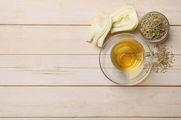 Aromatic fennel tea, seeds and fresh vegetable on wooden table, flat lay. Space for text
