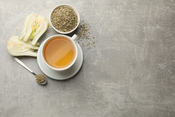 Aromatic fennel tea, seeds and fresh vegetable on grey table, flat lay. Space for text