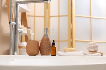 Different personal care products and accessories on bath tub in bathroom