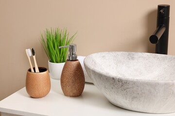 Different bath accessories and personal care products near sink on bathroom vanity