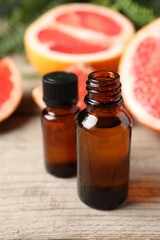 Grapefruit essential oil in bottles and fruits on wooden table