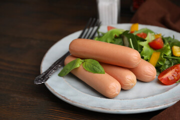 Delicious boiled sausages with salad on wooden table, closeup