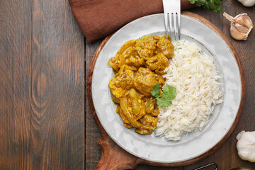 Delicious chicken curry with rice on wooden table, top view. Space for text