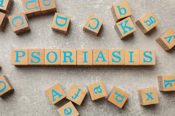Word Psoriasis made of wooden cubes with letters on light gray textured table, flat lay