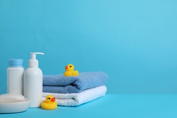 Baby cosmetic products, bath ducks and towels on light blue background. Space for text
