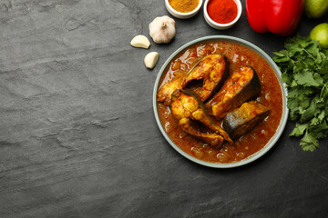 Tasty fish curry and ingredients on grey table, flat lay. Space for text. Indian cuisine